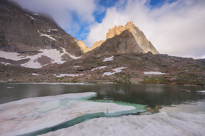 It was July 10th at Green Lake deep within the backcountry of Glacier Gorge but the lake still has yet to completely thaw out. The Spearhead formation rises above Green Lake as clouds streak above and over this famous formation. Technical Details: Nikon D810, Nikkor 16-35mm F4 VR