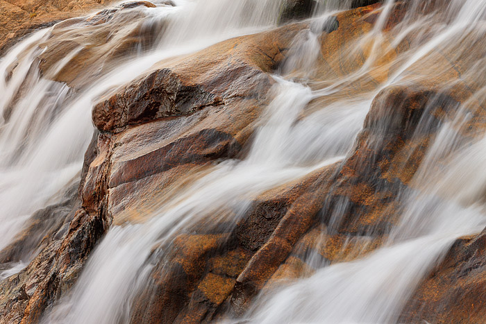 The rushing cascades of the Roaring River have helped to smooth and define the red hued rock that now makeup Alluvial Fan Falls...