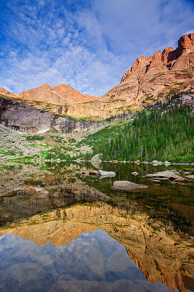 McHenry's Peak towers over a still Black Lake on a perfect morning in Rocky Mountain National Park. Clouds skirt over McHenry...