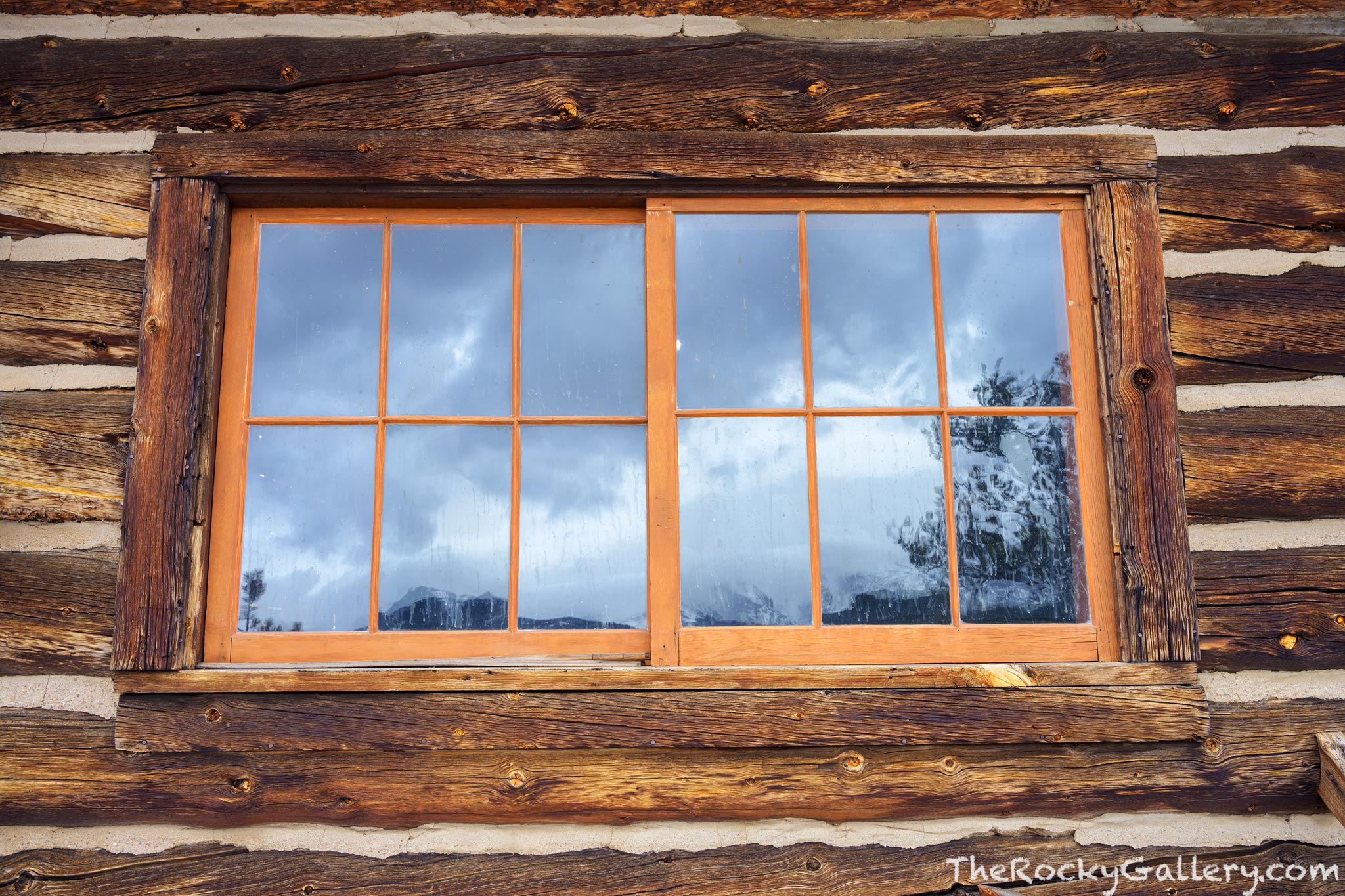 A window on a cabin overlooking Moraine Park reflects clouds and snow swirling over the Continental Divide. This craftmanship...