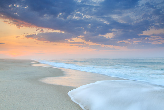 Pastel colors light the sky and color the sea at daybreak over Dune Beach. The sea mist in the air combined with the colors of...