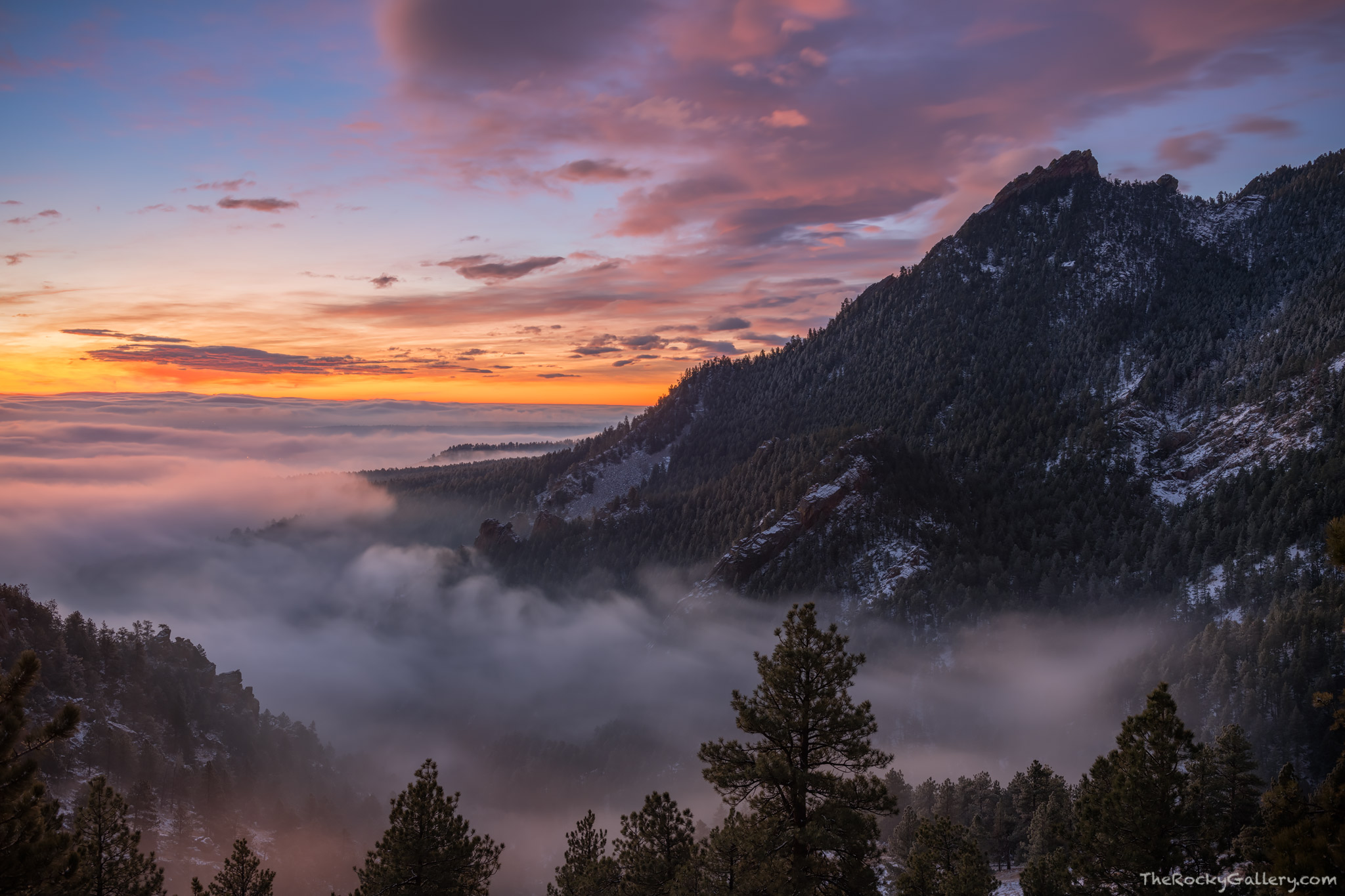 Sunrise unfolds over the Flatirons of Boulder, Colorado high above Chautauqua Park and Gregory Canyon. Fog from and inversion...