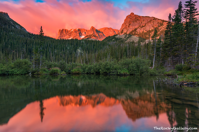 Clouds roll over Notchtop Mountain and the Little Matterhorn as the new days sun turns the sky and mountains shades of pink and...