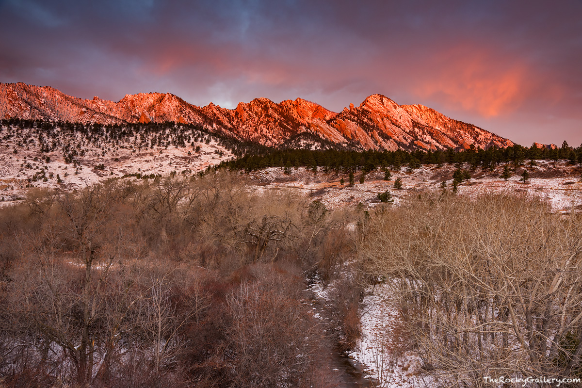 The Flatirons glow red as the first rays of sun of a new winter day illuminate these iconic monoliths. It's the first day of...