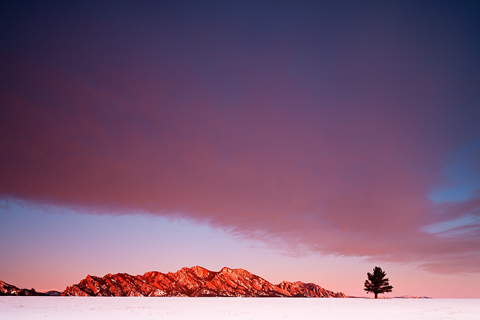 A beautiful wave clouds sits over Boulder's Flatirons as the first rays of sunrise turn the famous formation a brilliant red....