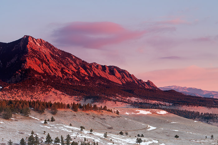 Pink hued clouds drift overtop of Boulder's Flatiron formation on a spectacular morning. This view from Open Space and Mountain...