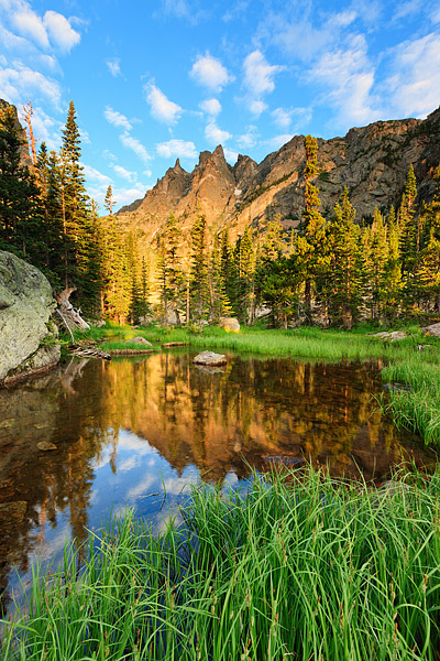 The morning sun illuminates Flattop Mountain in Rocky Mountain National Park. Flattop Mountain reflects in a small tarn formed...