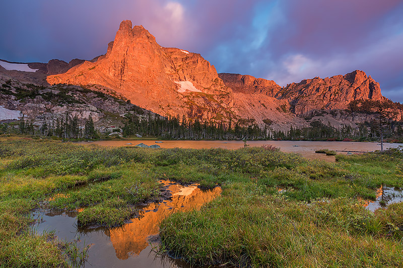 Autumn is beginning to color the grasses and scrub around Lake Helene in yellows and reds. Sunrise colors Notchtop Mountain in...