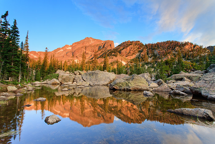 Wispy clouds skirt over Hallet Peak and Lake Haiyaha on a perfect summer morning in Rocky Mountain National Park. The rocky shores...