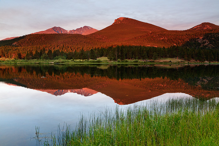 The reflections of Longs Peak, Mount Meeker and the Estes Cone glow on the placid surface of Rocky Mountain National Park's Lily...