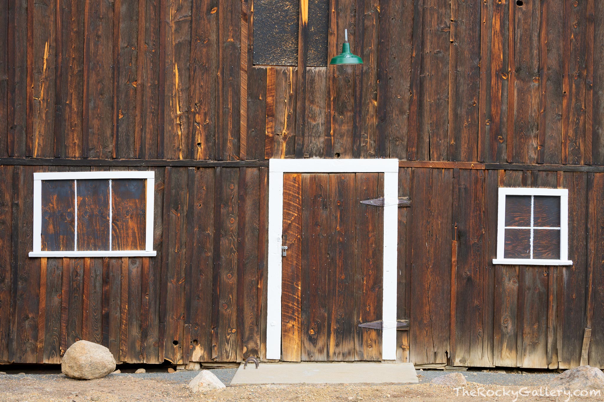 The south door on the McGraw Ranch barn is simple, but elegant. The weather wood, boarded up windows and one metal green light...