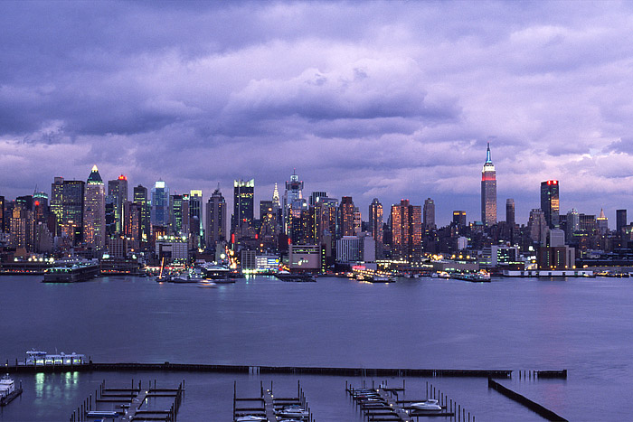 The sun starts to set over New York City and Midtown Manhattan. The Hudson River reflects the pastel colors as the sun dips below...
