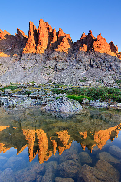The famous Cathedral Spires formation rises above Sky Pond on a clear and calm summer morning. World famous with rock climbers...