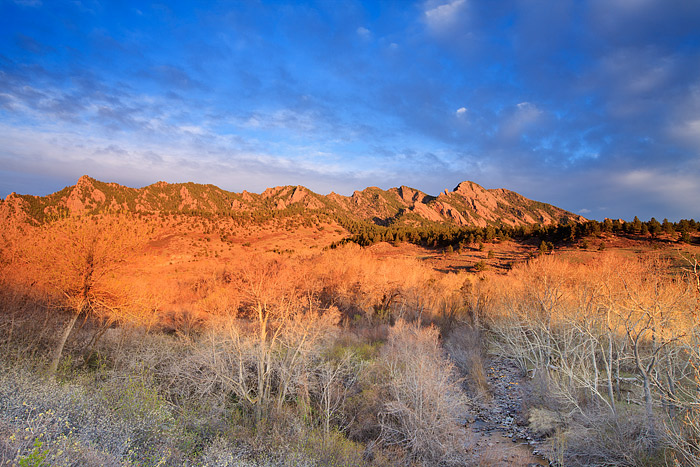 The cloud cover over the south end of the Flatirons and South Boulder Peak open up just enough to allow for the first rays of...