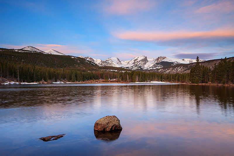 It's late spring at Sprague Lake. The ice has finally thawed from the surface of the lake but Otis Peak, Hallet Peak and Flattop...