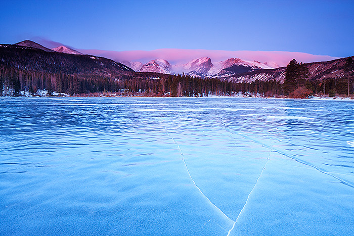 A frozen and wind swept Sprague Lake awakens as the winter sunrise lights up the peaks of Rocky Mountain National Park. Thatchtop...